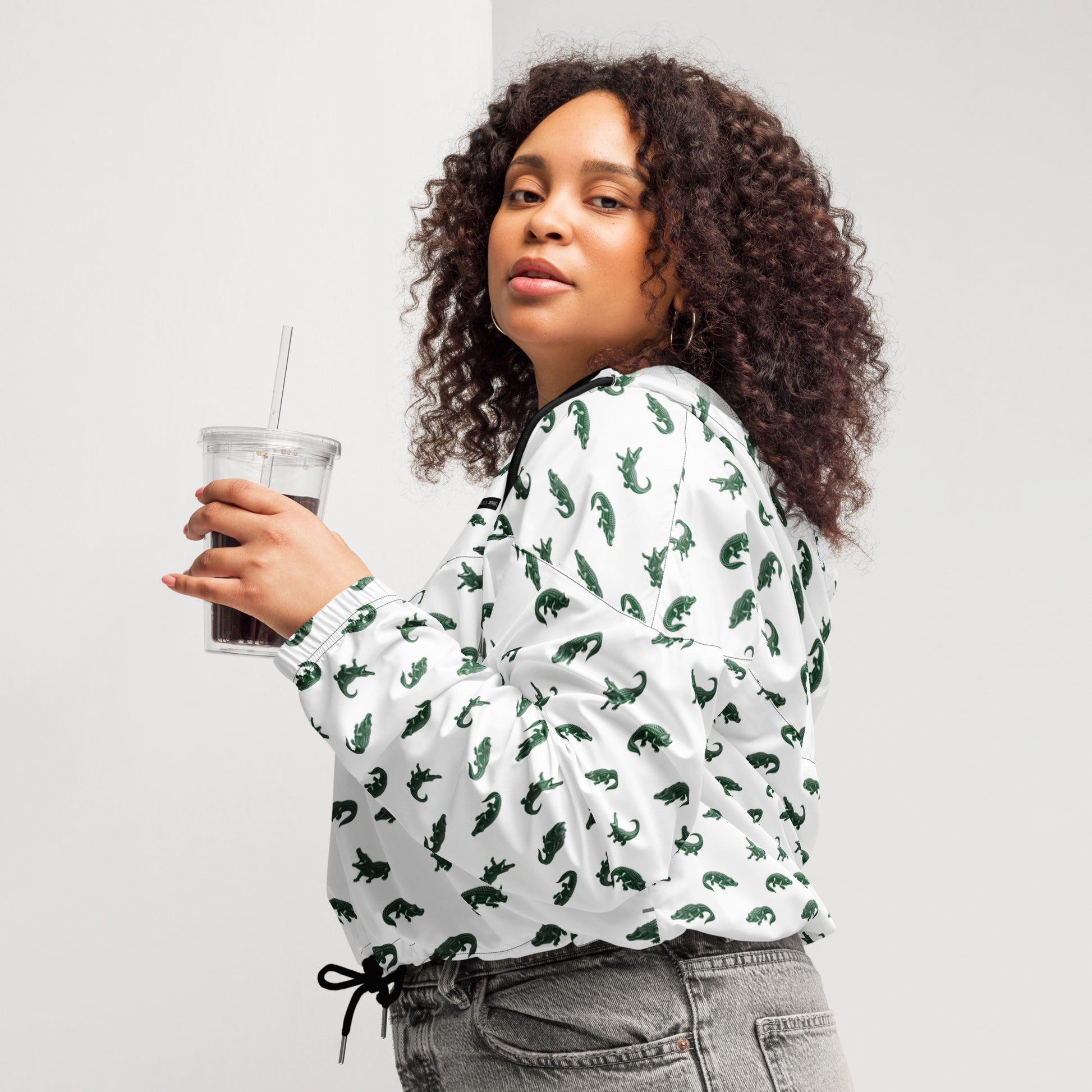 Woman wearing white, cropped windbreaker with pattern of green alligators.