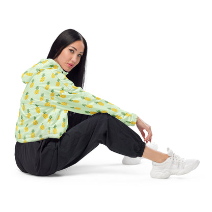 Woman wearing cropped jacket with pattern of pineapples set on a light-green background.