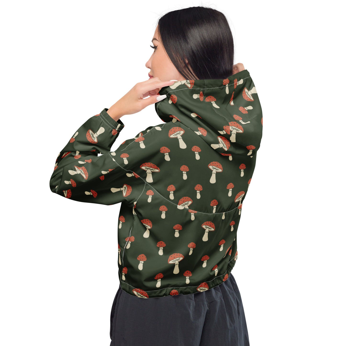 Woman wearing cropped jacket with pattern of mushrooms set on a green background.