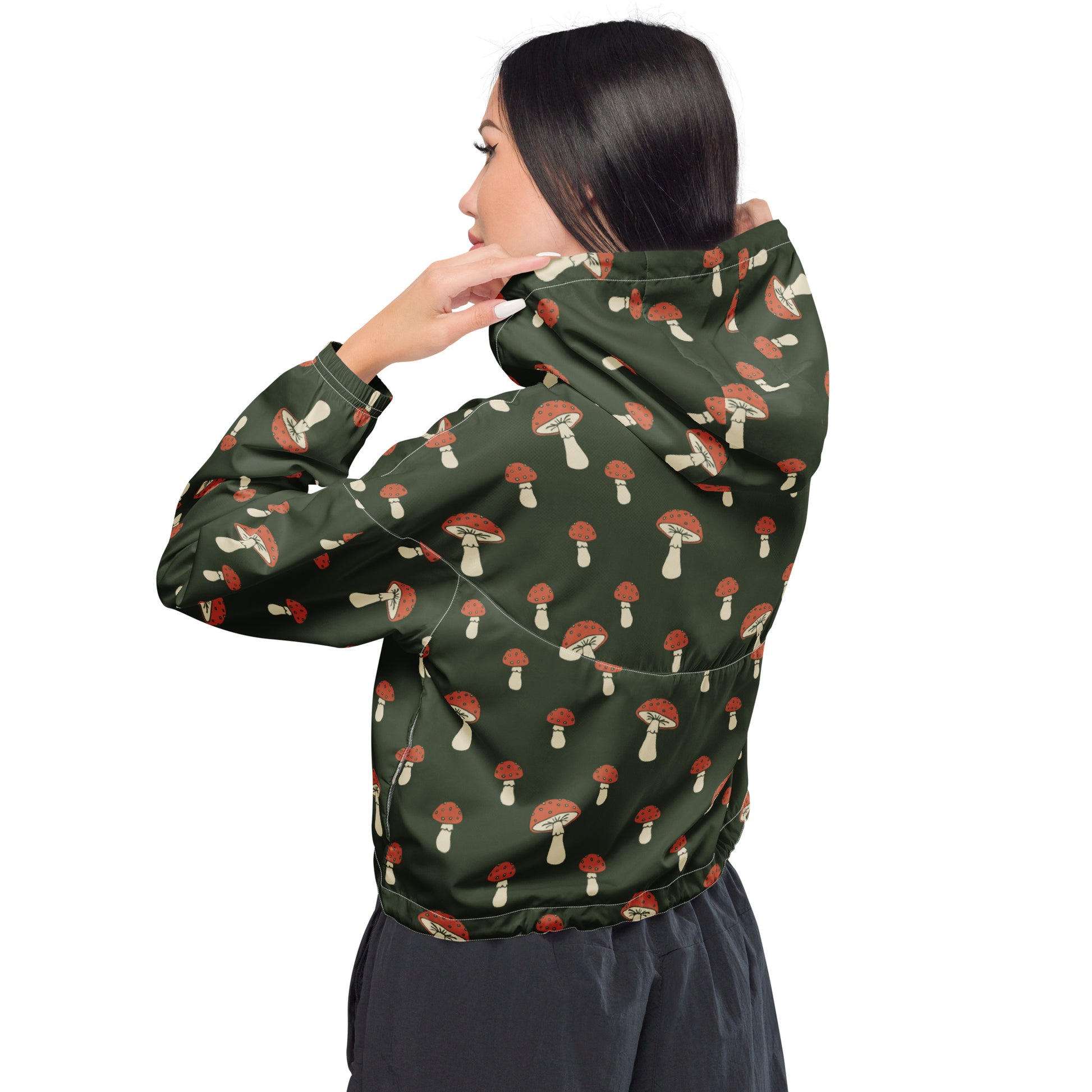 Woman wearing cropped jacket with pattern of mushrooms set on a green background.