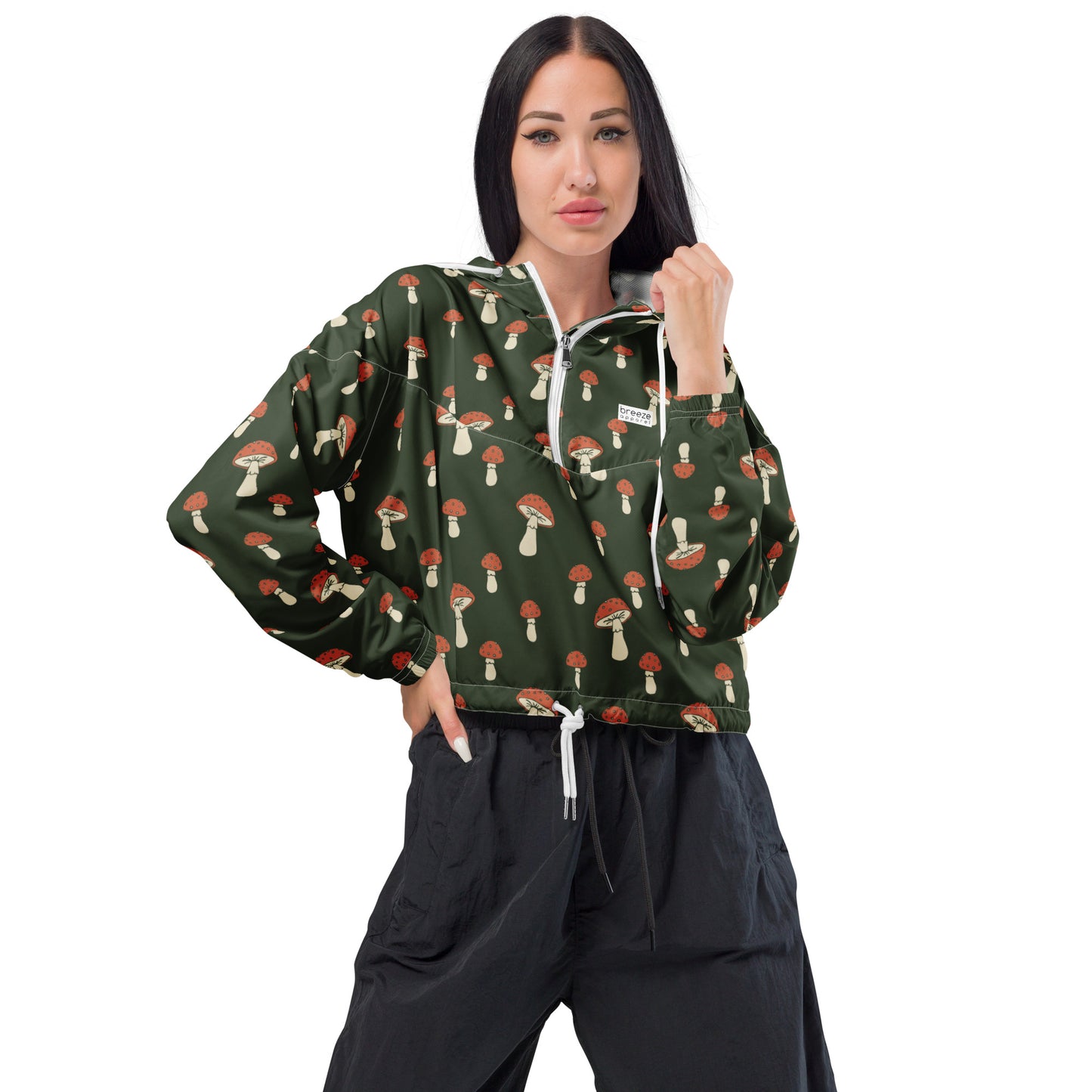 Woman wearing cropped jacket with pattern of mushrooms set on a green background.