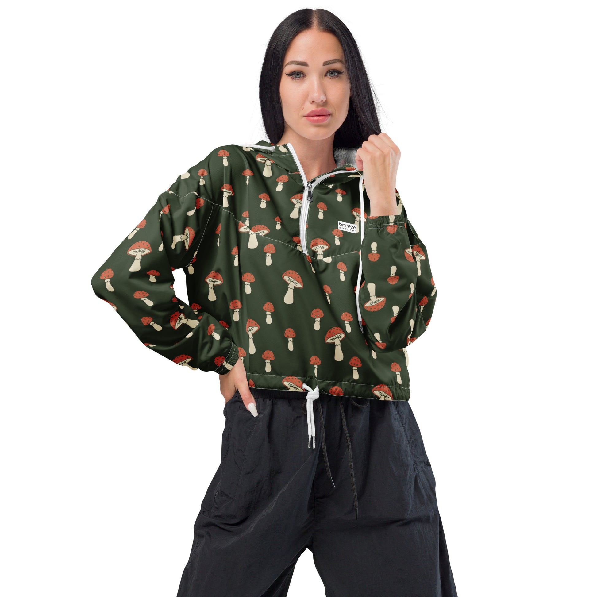 Woman wearing cropped jacket with pattern of mushrooms set on a green background.