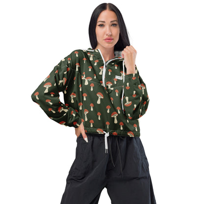 Woman wearing cropped jacket with pattern of mushrooms set on a green background.