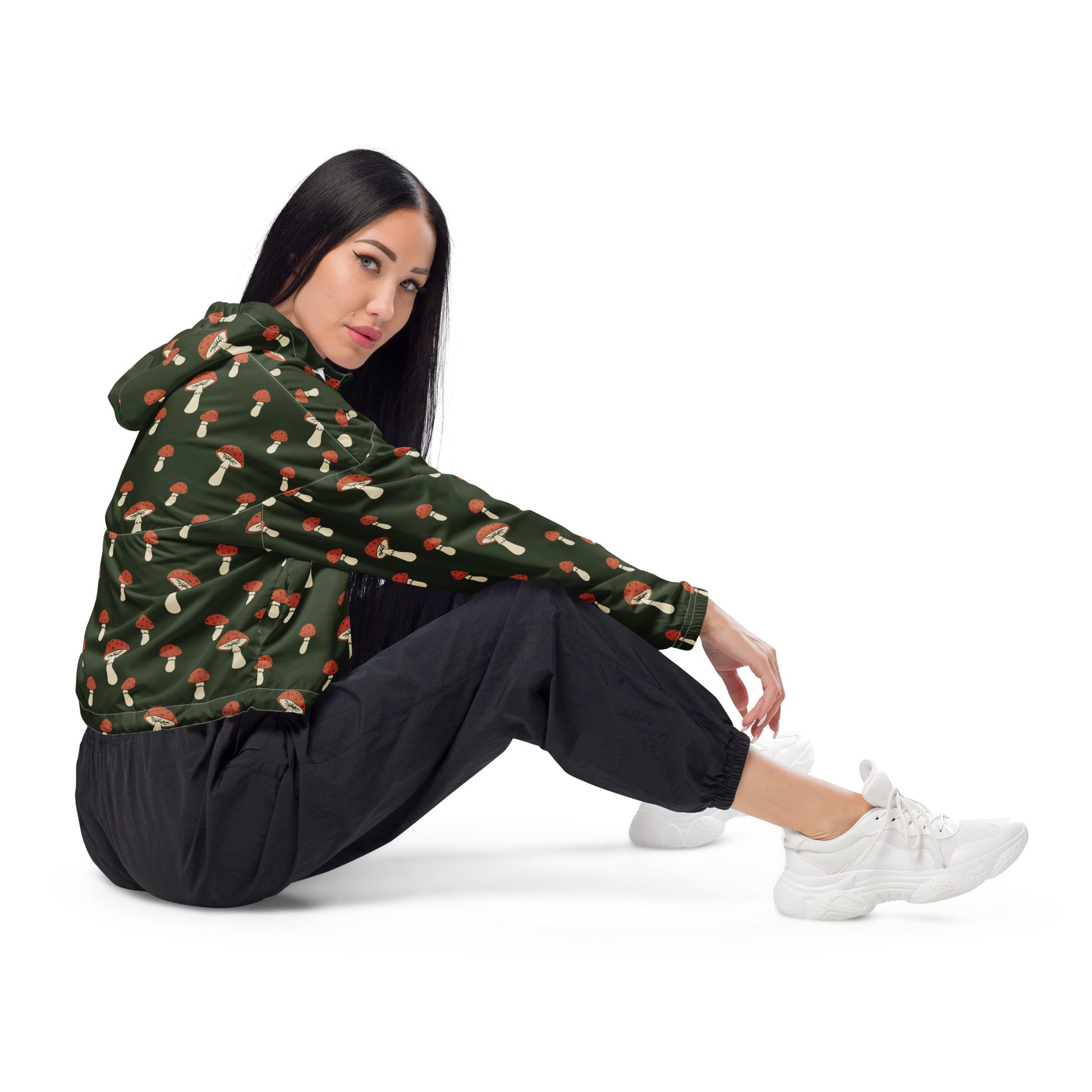 Woman wearing cropped jacket with pattern of mushrooms set on a green background.