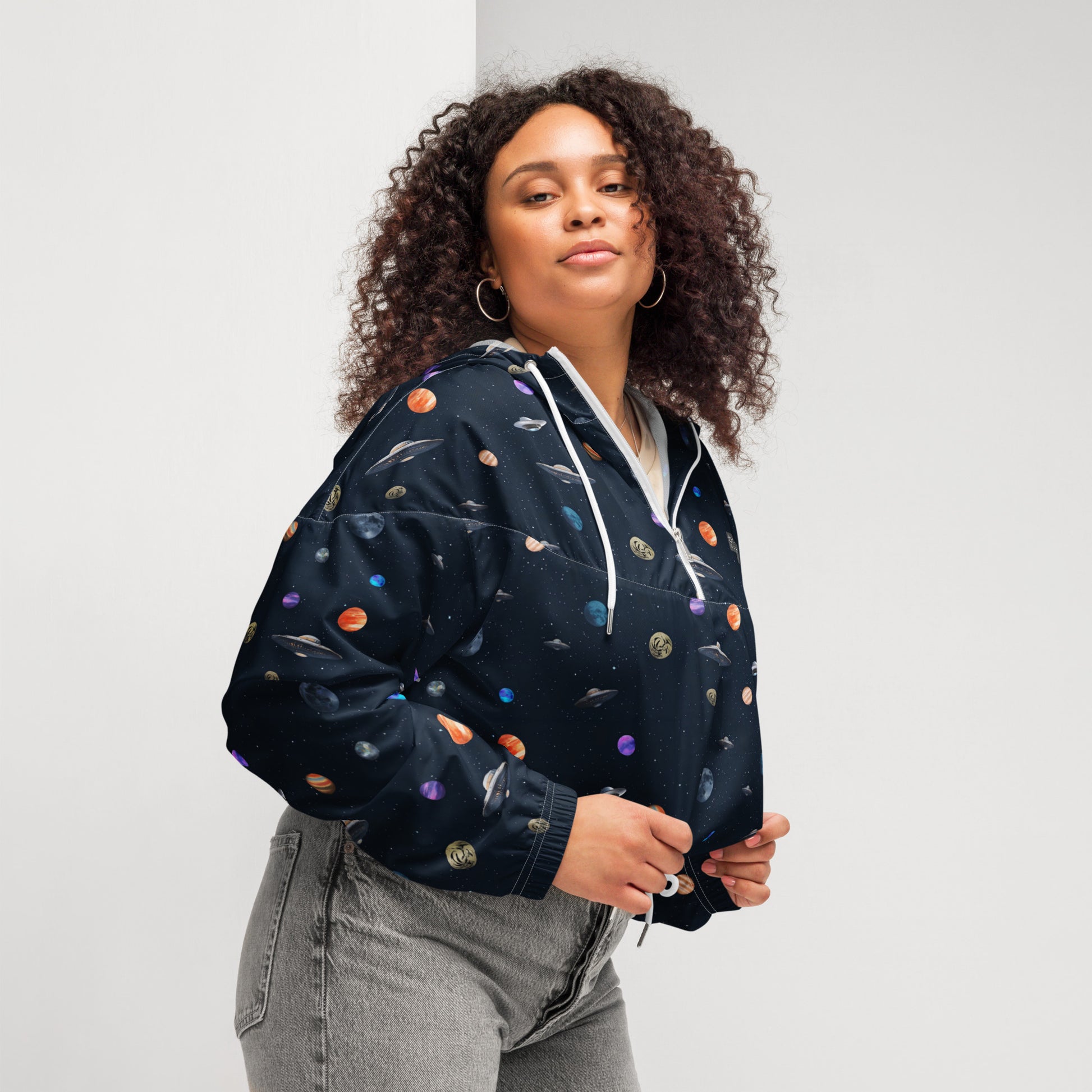 Woman wearing cropped windbreaker with pattern of UFOs and planets in space.
