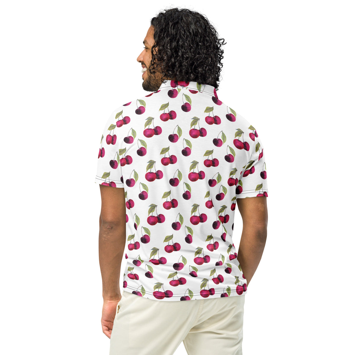 Rear view of man wearing polo with pattern of cherries set on a white background.