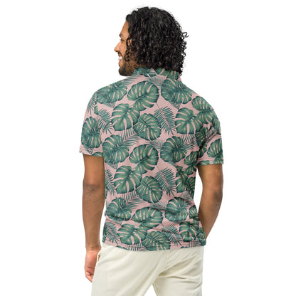 Rear view of man wearing polo with pattern of green palm leaves set on a light-pink background.