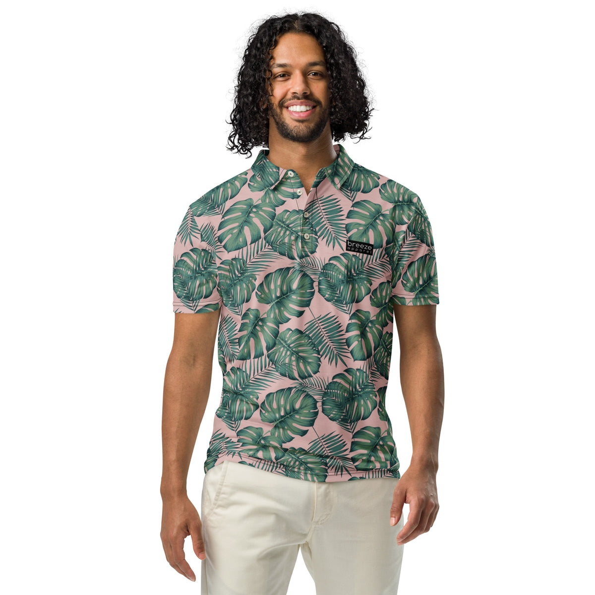 Man wearing polo with pattern of green palm leaves set on a light-pink background.