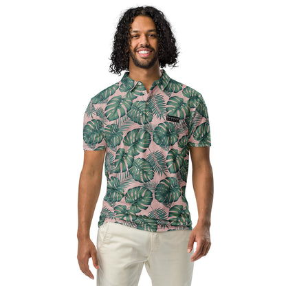 Man wearing polo with pattern of green palm leaves set on a light-pink background.