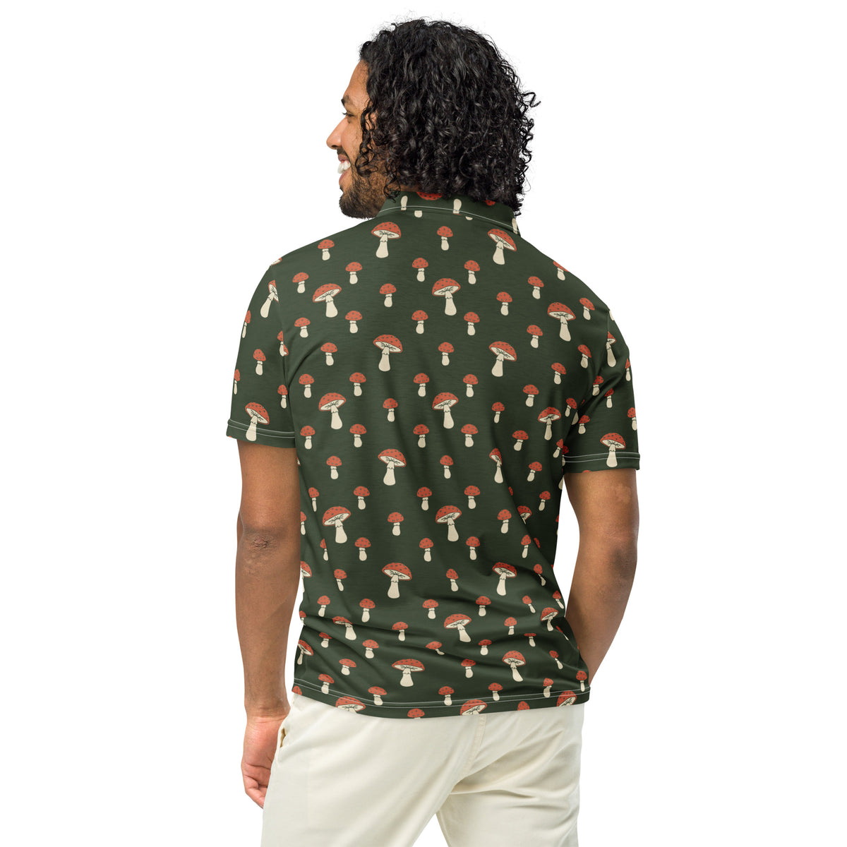 Rear view of man wearing polo with pattern of white-and-red mushrooms set on a dark-green background.