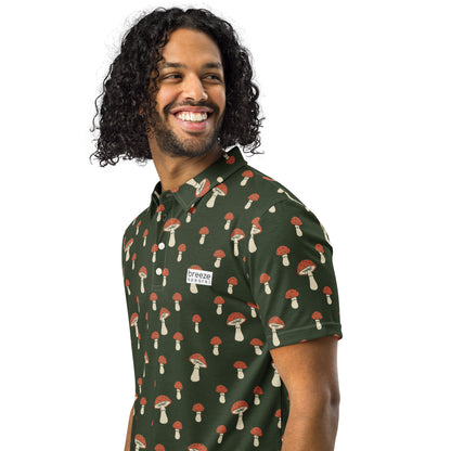Man wearing polo with pattern of white-and-red mushrooms set on a dark-green background.