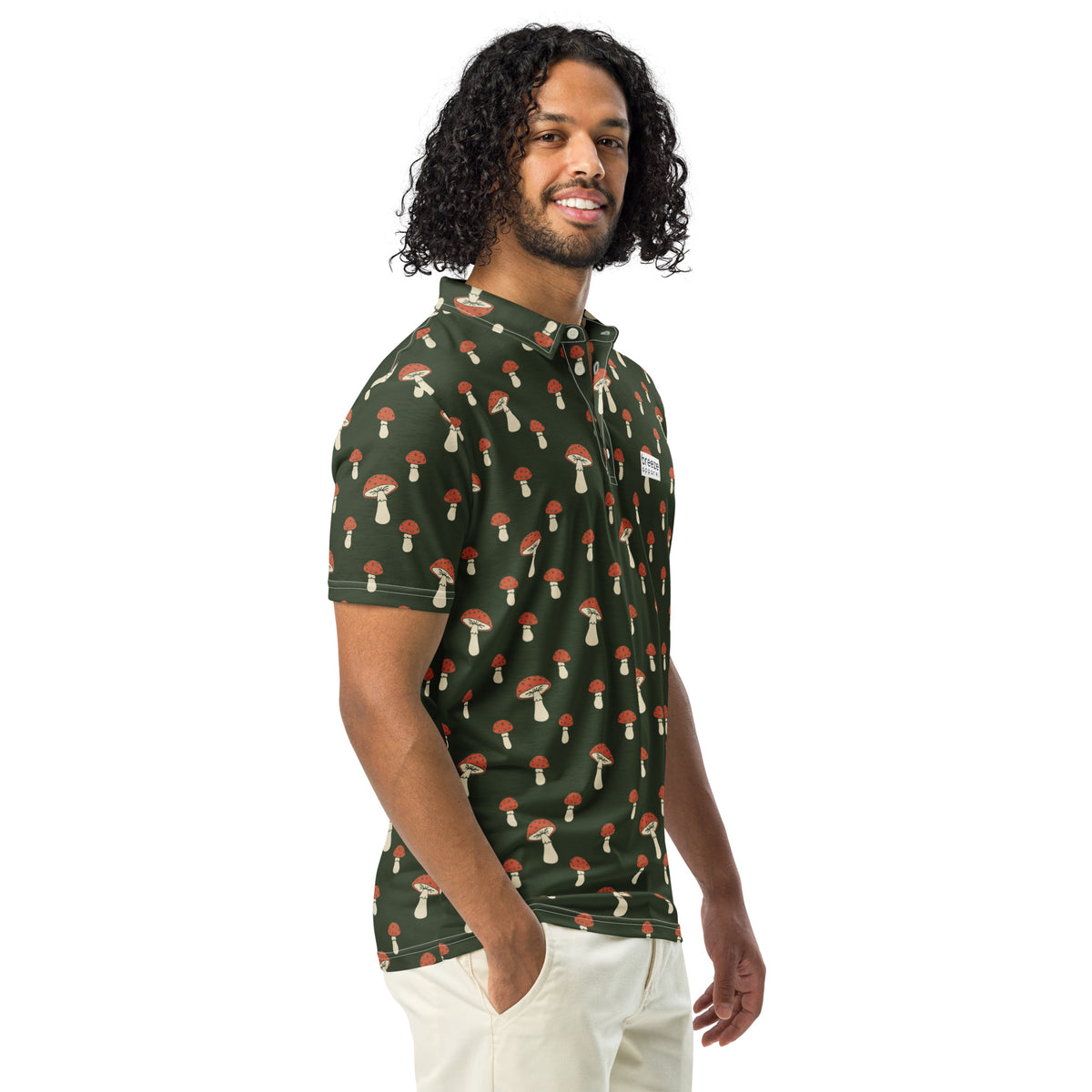 Man wearing polo with pattern of white-and-red mushrooms set on a dark-green background.