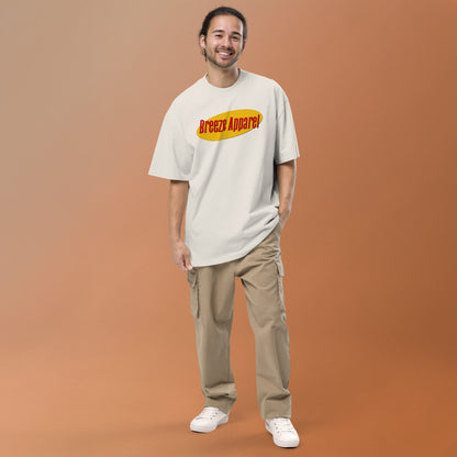 Man wearing white, oversized t-shirt with graphic of red lettering set over yellow oval.