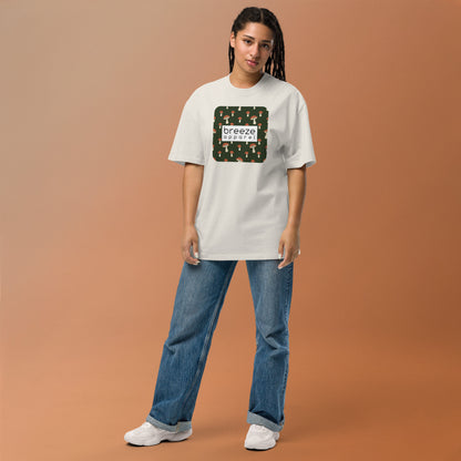 Woman wearing white, oversized t-shirt with square graphic of mushrooms on a green background and overlaid with white, rectangular logo.