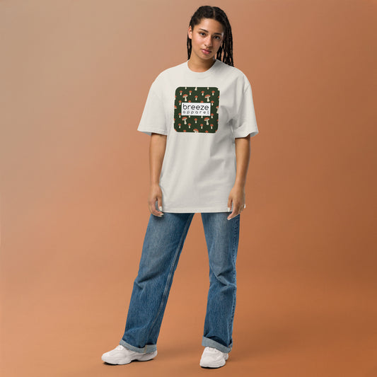 Woman wearing white, oversized t-shirt with square graphic of mushrooms on a green background and overlaid with white, rectangular logo.