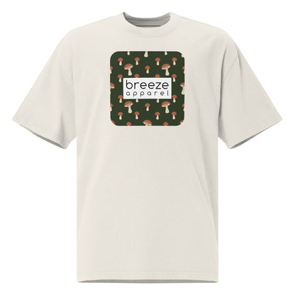 White t-shirt with square graphic of mushrooms on a green background and overlaid with white, rectangular logo.