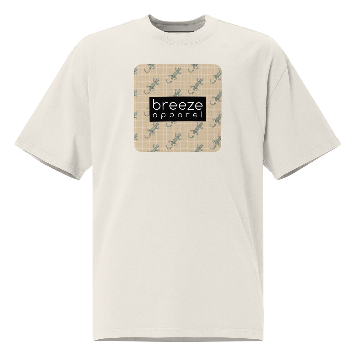 White t-shirt with square over chest that contains pattern of green geckos set on beige background, overlaid with black, rectangular logo with white lettering.