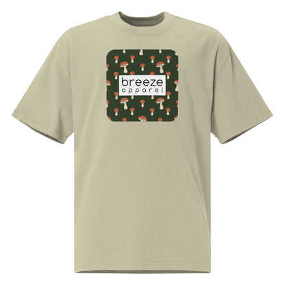 Green t-shirt with square graphic of mushrooms on a green background and overlaid with white, rectangular logo.