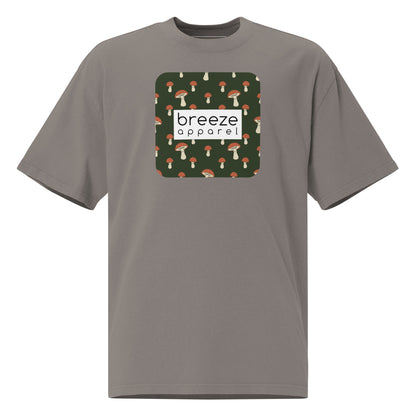 Gray t-shirt with square graphic of mushrooms on a green background and overlaid with white, rectangular logo.