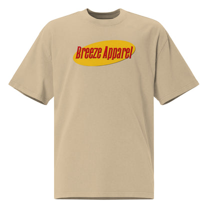 Tan t-shirt with graphic of red lettering set over yellow oval.