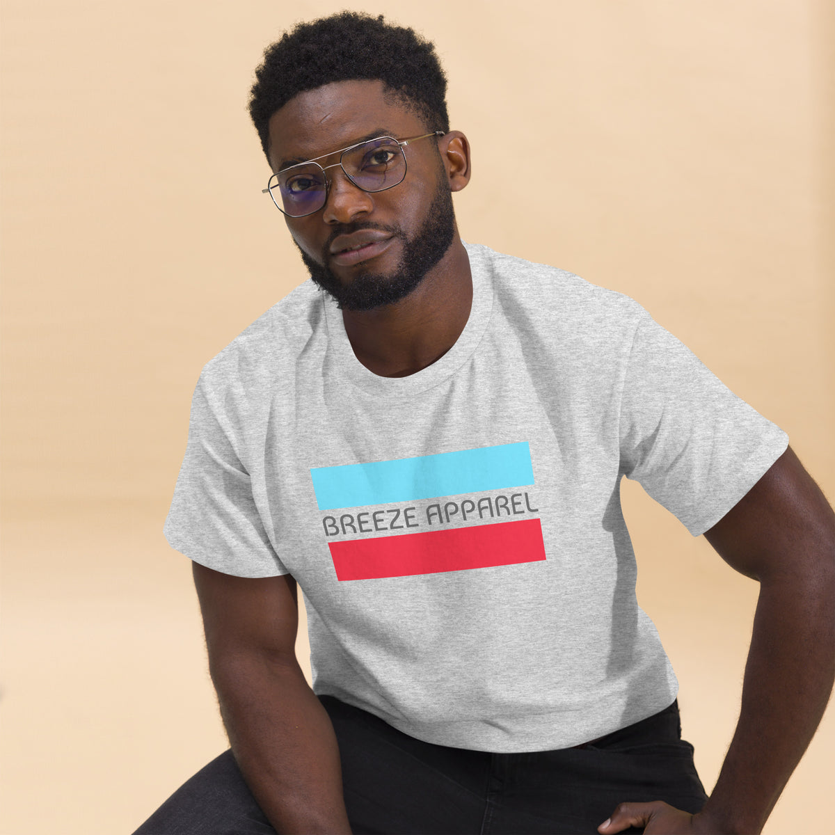 Man wearing ash-gray t-shirt with gray 'Breeze Apparel' logo between horizontal bars, the top being light blue and the bottom being red