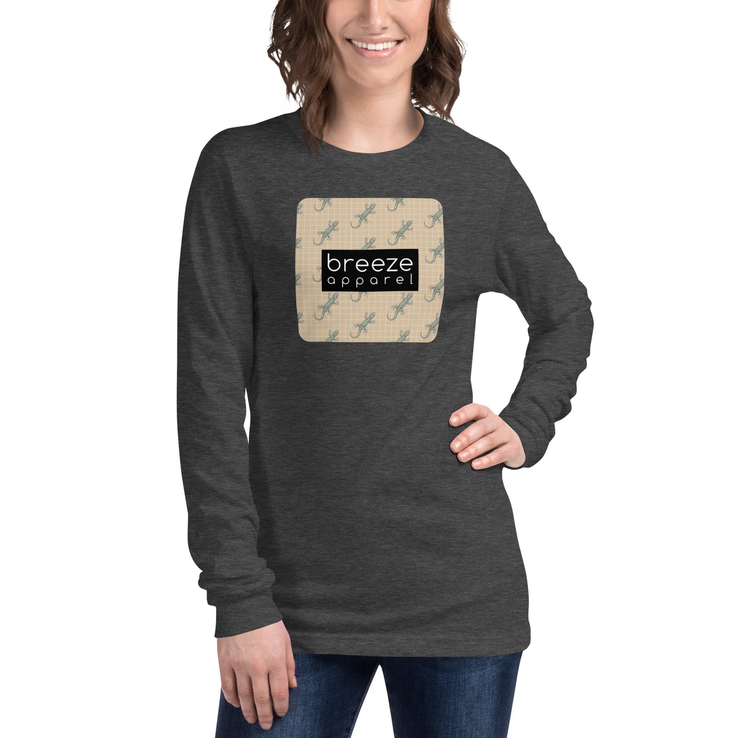 Woman wearing gray, long-sleeved shirt with square over chest that contains pattern of green geckos set on beige background, overlaid with black, rectangular logo with white lettering.