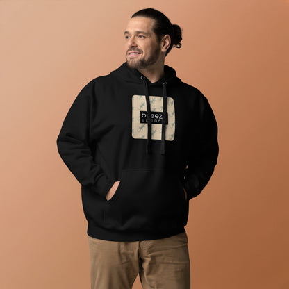 Man wearing black hoodie with square over chest that contains pattern of green geckos set on beige background, overlaid with black, rectangular logo with white lettering.