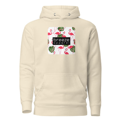 Beige hoodie with graphic of flamingos and green palm leaves set on a white background and overlaid with a black, rectangular logo.