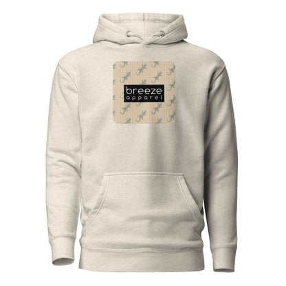 Beige hoodie with square over chest that contains pattern of green geckos set on beige background, overlaid with black, rectangular logo with white lettering.
