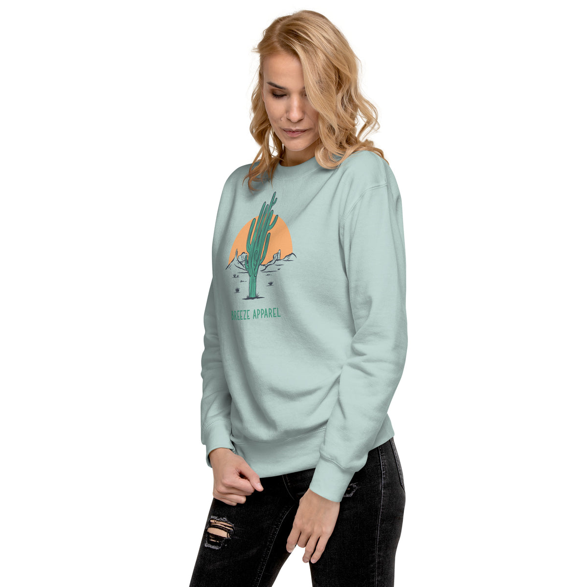 Woman wearing silver-blue sweatshirt with graphic of cactus and sun.
