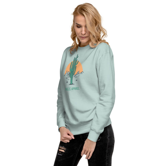Woman wearing silver-blue sweatshirt with graphic of cactus and sun.