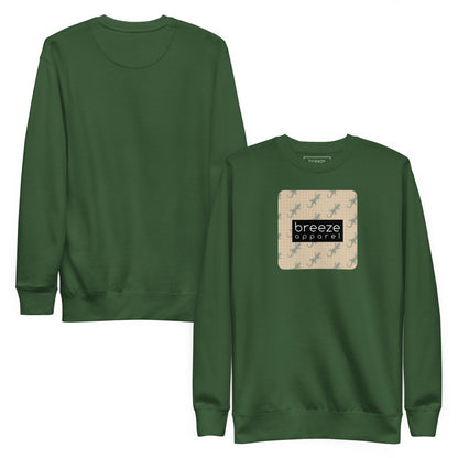 Green sweatshirt with square over chest that contains pattern of green geckos set on beige background, overlaid with black, rectangular logo with white lettering. Plain back also shown.