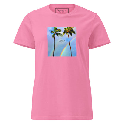 Azalea-pink t-shirt with a graphic of palm trees, rainbow, and a clear blue sky in the background. A small, black 'breeze apparel' logo is between the trees. 