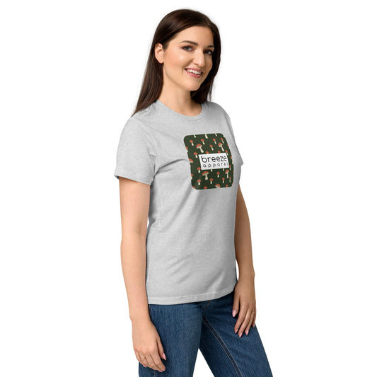Woman wearing gray t-shirt with graphic of mushroom pattern set on a green background, overlaid with a white box with 'breeze apparel' in black inside.