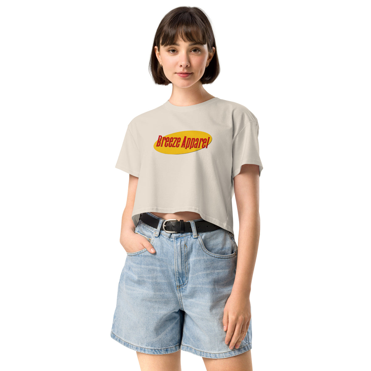 Woman wearing cream crop top with graphic with red lettering set on a yellow oval. 