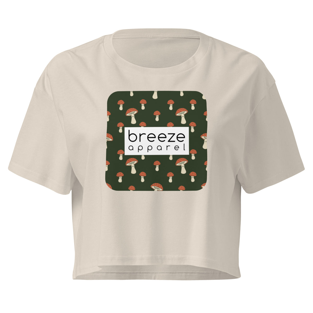 Cream crop top with graphic of mushrooms set on a green background and overlaid with a white rectangle logo.