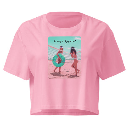 Pink crop top with graphic of two women in bikinis talking on the beach.