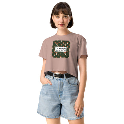 Woman wearing pink crop top with graphic of mushrooms set on a green background and overlaid with a white rectangle logo.
