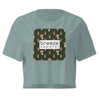 Green crop top with graphic of mushrooms set on a green background and overlaid with a white rectangle logo.