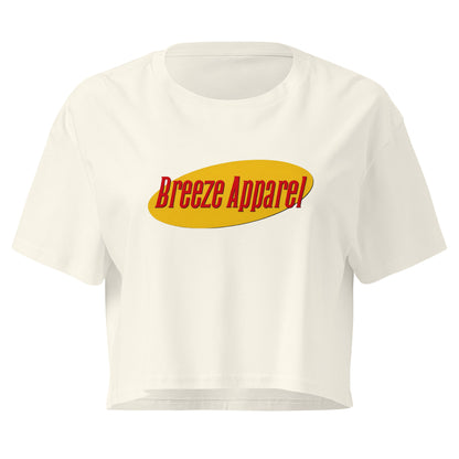 White crop top with graphic with red lettering set on a yellow oval. 