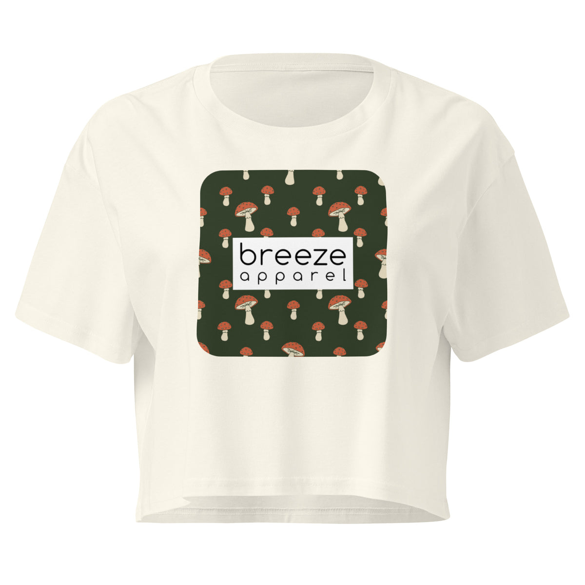 Cream crop top with graphic of mushrooms set on a green background and overlaid with a white rectangle logo.