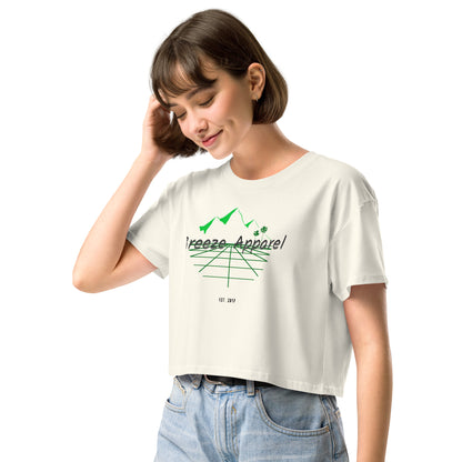 Woman wearing cream crop top with graphic of palm trees and mountains.