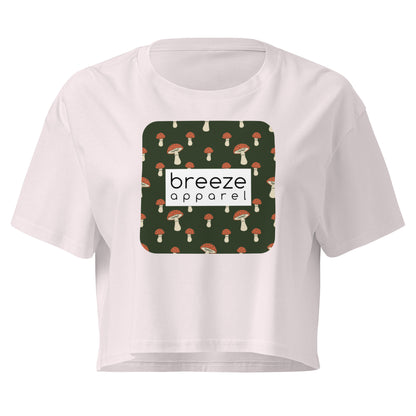 Orchid crop top with graphic of mushrooms set on a green background and overlaid with a white rectangle logo.