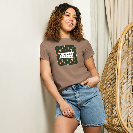 Woman wearing brown t-shirt with design of mushrooms set on green background and overlaid with a white rectangle with 'breeze apparel' in black inside.