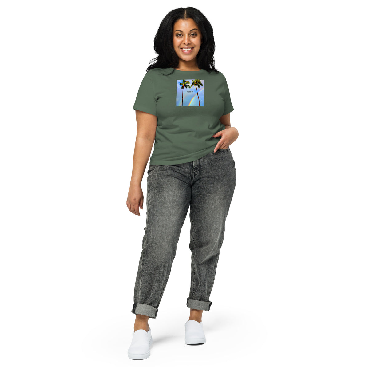 Woman wearing pine-green t-shirt with a graphic of palm trees, rainbow, and a clear blue sky in the background. A small, black 'breeze apparel' logo is between the trees.
