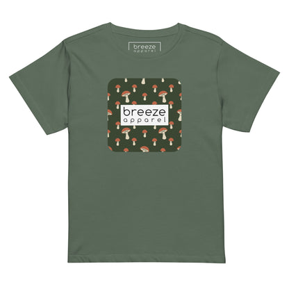 Pine-green t-shirt with design of mushrooms set on green background and overlaid with a white rectangle with 'breeze apparel' in black inside.