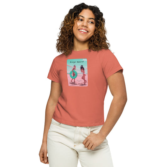 Woman wearing red-sorbet t-shirt with an image of two women in bikinis on the beach, standing by a volleyball net, one holding a swim ring and smiling, the other leaning on the net, with inscription in black of 'breeze apparel' towards the top of the image, and 'fun in the sun' in black on the ground between the women. 