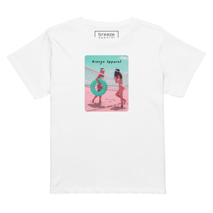 White t-shirt with an image of two women in bikinis on the beach, standing by a volleyball net, one holding a swim ring and smiling, the other leaning on the net, with inscription in black of 'breeze apparel' towards the top of the image, and 'fun in the sun' in black on the ground between the women. 