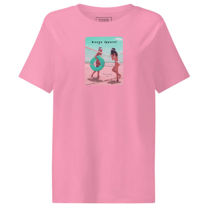 Pink t-shirt with an image of two women in bikinis on the beach, standing by a volleyball net, one holding a swim ring and smiling, the other leaning on the net, with inscription in black of 'breeze apparel' towards the top of the image, and 'fun in the sun' in black on the ground between the women. 