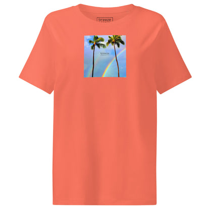 Fiesta-orange t-shirt with a graphic of palm trees, rainbow, and a clear blue sky in the background. A small, black 'breeze apparel' logo is between the trees.